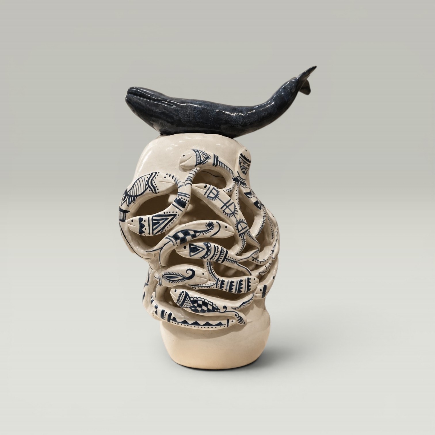 Forms in Motions: openwork ceramic vessel of patterned fish with a dark fish form above